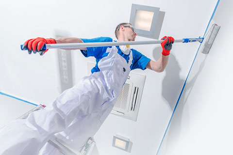 Young man painting an interior room.